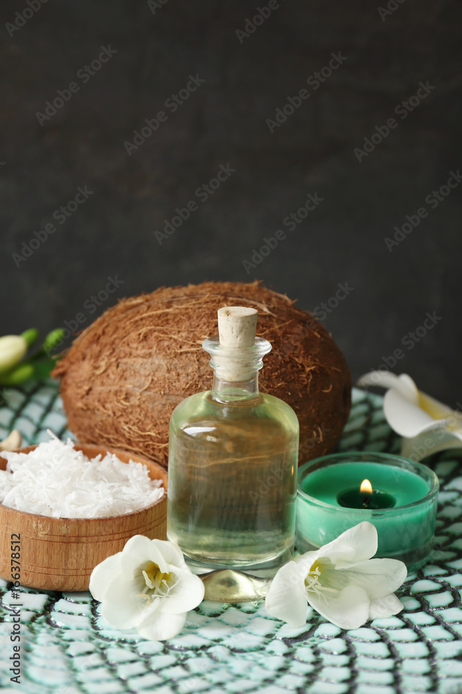 Bottle with oil, desiccated coconut and candle on grey background Bottle with oil, desiccated coconut and candle on grey background