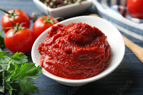 Fototapeta Ceramic bowl with tomato sauce and ingredients on wooden table