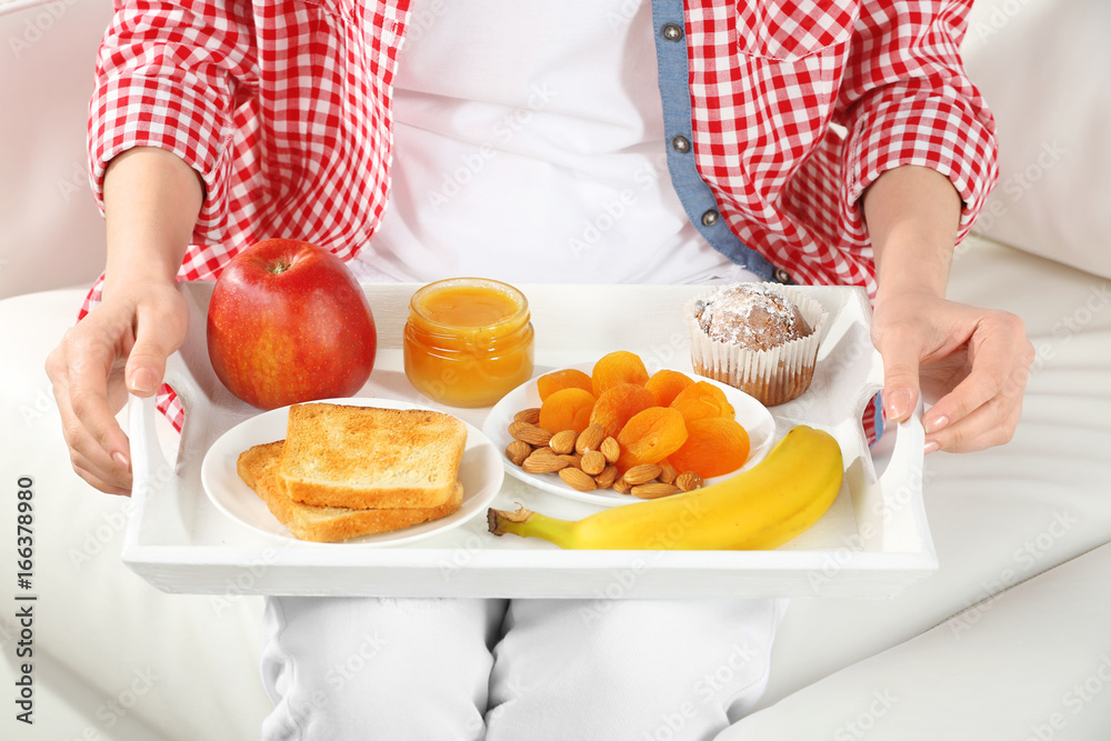 Young woman having breakfast on sofa