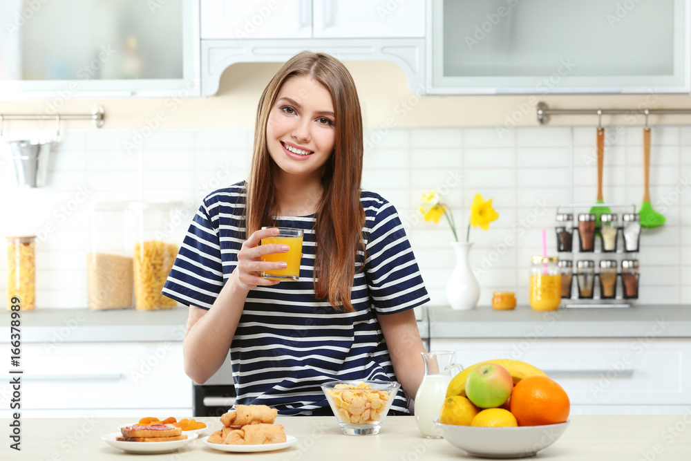 Young beautiful woman having breakfast at kitchen