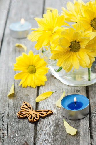 Fresh yellow daisy flowers  butterfly and lit candle