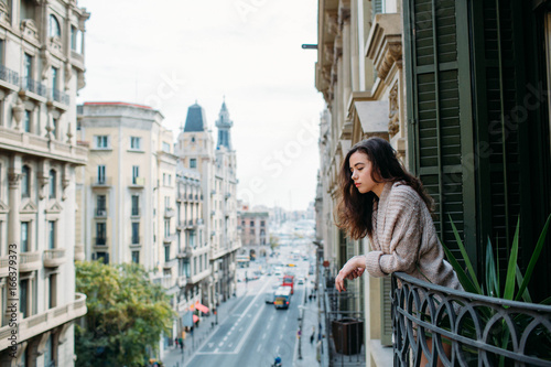 Woman looking down the street from her balcony photo