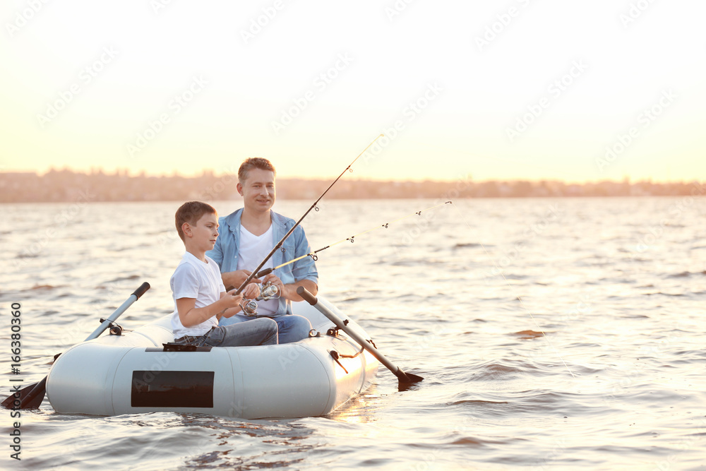 Dad and son fishing from inflatable boat on river Dad and son fishing from inflatable boat on river