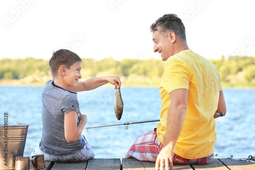 Dad and son with caught fish on pier