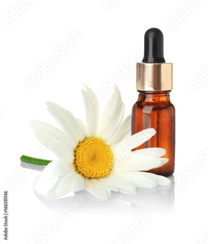 Bottle of essential oil and chamomile flower on white background