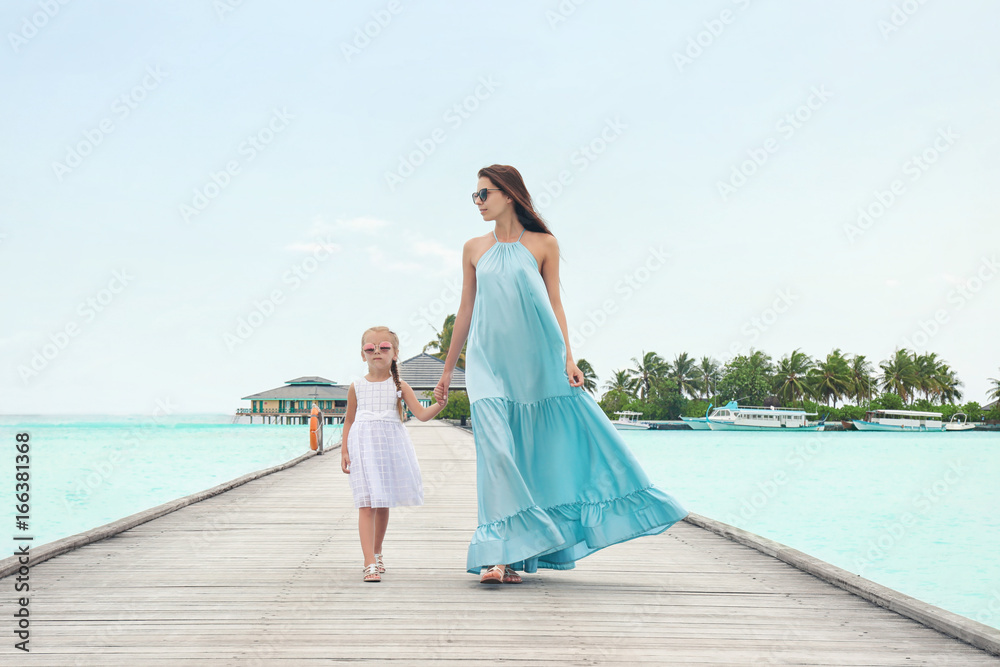 Beautiful young woman with her daughter at sea resort