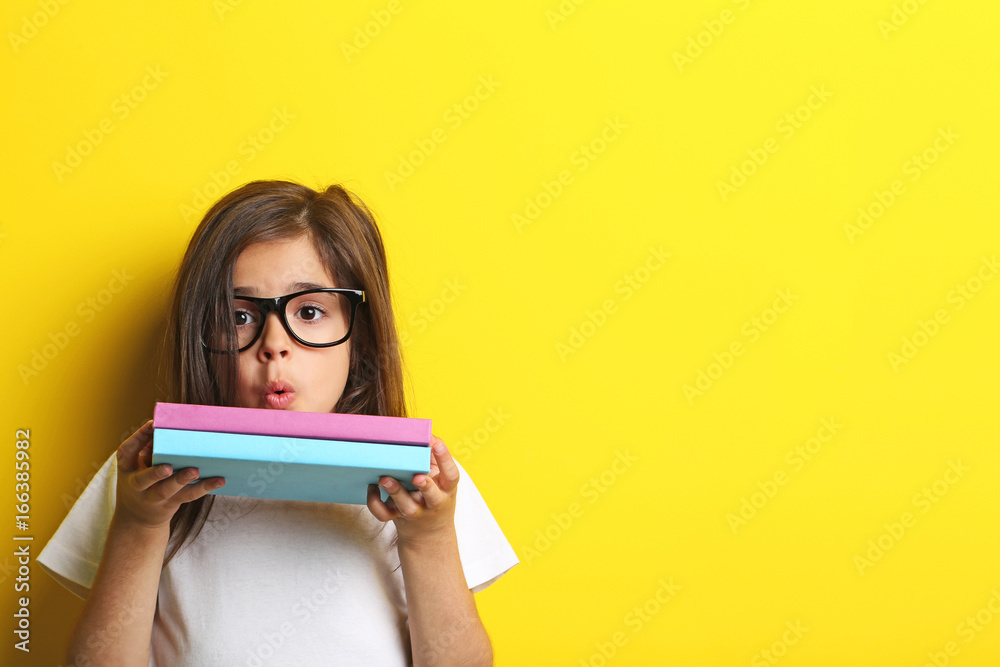 Beautiful little girl with glasses and books on yellow background Beautiful little girl with glasses and books on yellow background