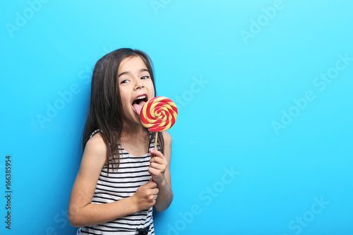 Fotografie Beautiful little girl with lollipop on blue background