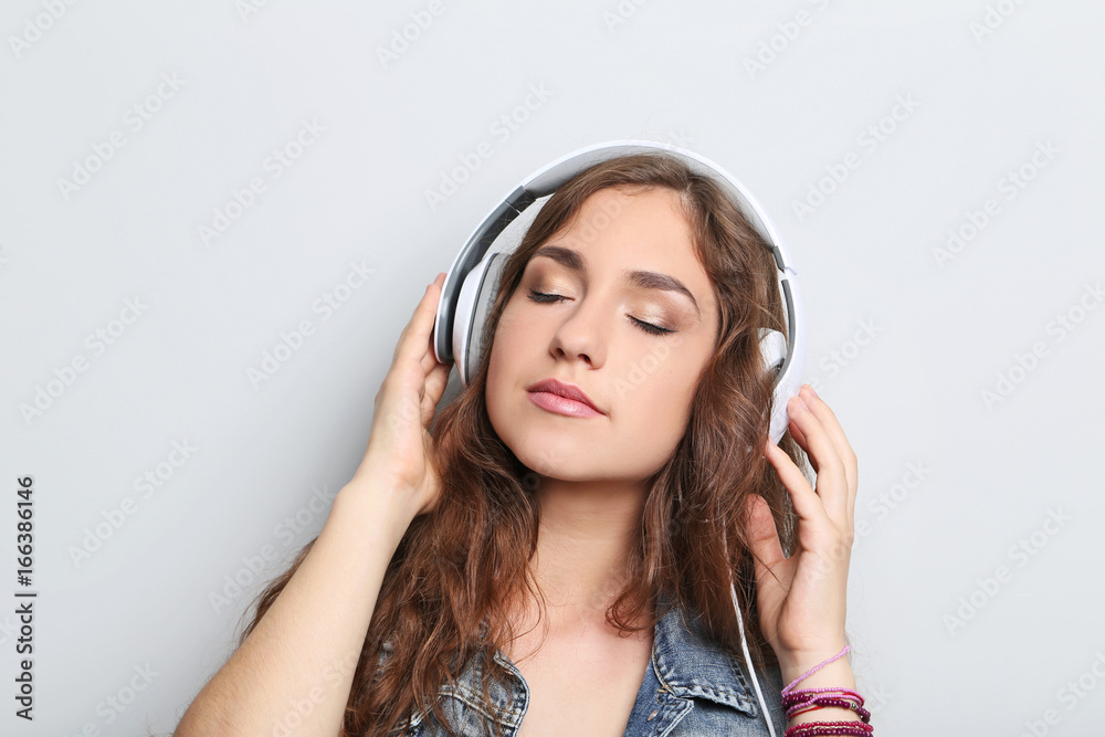 Portrait of young woman with headphones on grey background Portrait of young woman with headphones on grey background