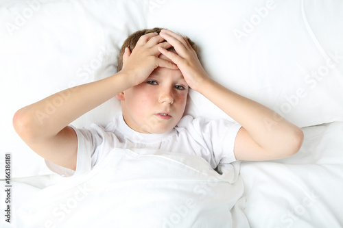 Sick boy lying in white bed