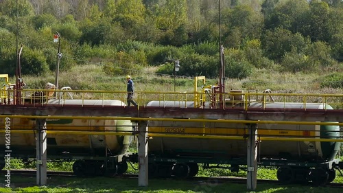 Railway Station. Train Staying on Road. Worker Walking on Platform Over Car Cisterns. Man Checking Pipes. Forest on Backgrond. Summer