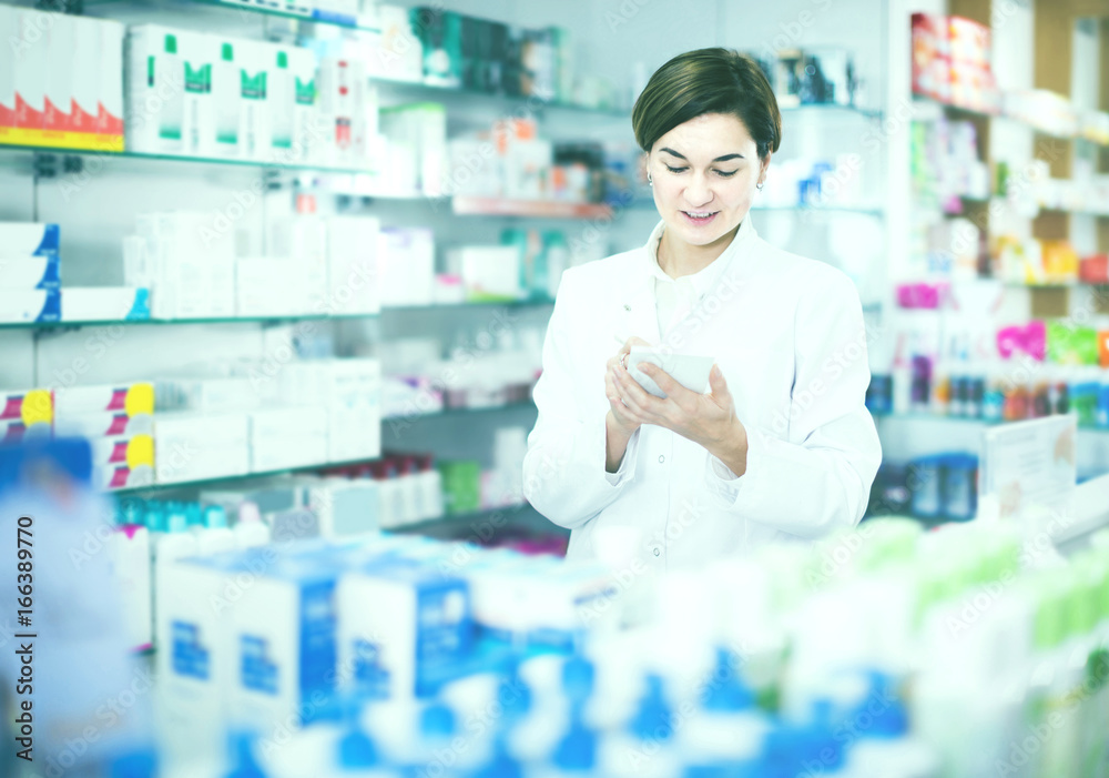 female pharmacist checking assortment of drugs in pharmacy