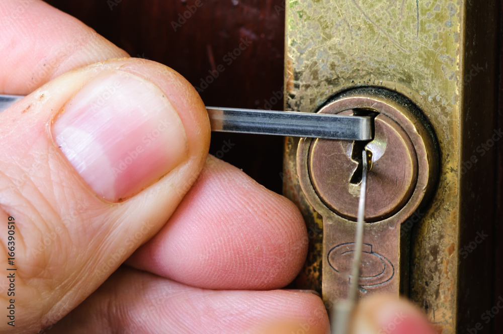 A man uses lockpicking tools to pick the lock of a house. Stock Photo