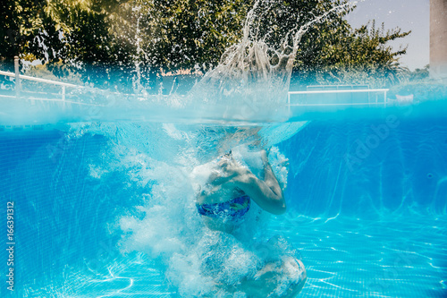 .Young woman enjoying the pool on a sunny summer day. Taking photos under water playful. Lifestyle portrait. © lubero