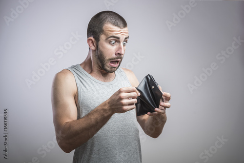 A close-up portrait of a shocked, surprised speechless man, holding an empty wallet