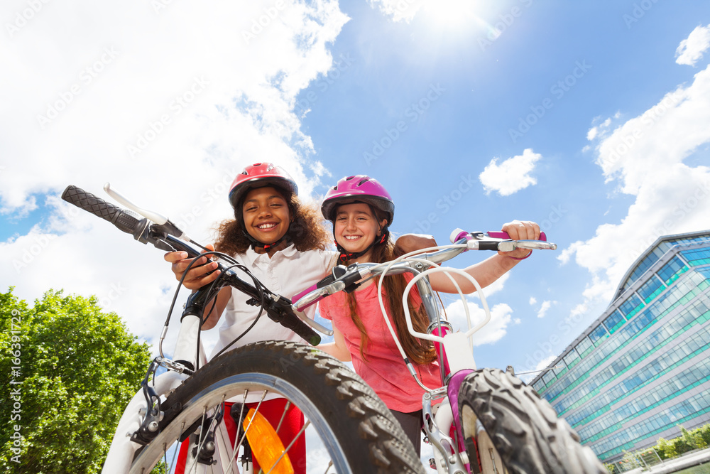Fototapeta premium happy girl-friends hugging and holding bicycles