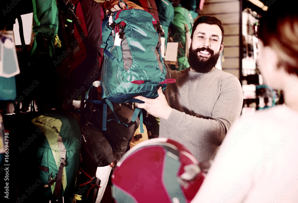 Fototapeta premium Man shows the girl a blue backpack