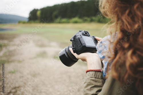 Young woman reviewing her photographs on dslr camera in the mountain photo