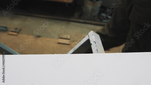 Unrecognisable woodworker using yellow ruler tape to mesaure plank of wood in workshop, close up photo