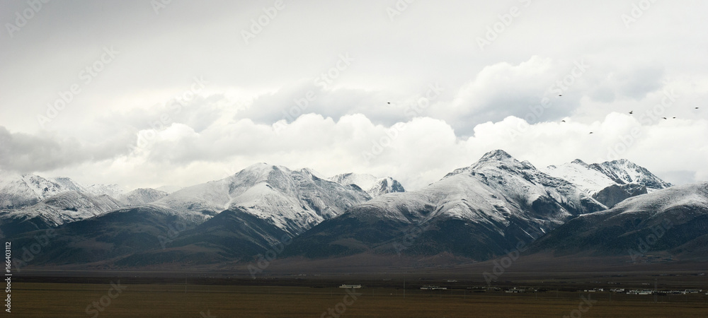 Snowy mountains in clouds in Tibet panorama view