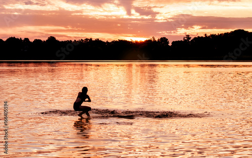 Kids and families are having fun at a lake under sunset 