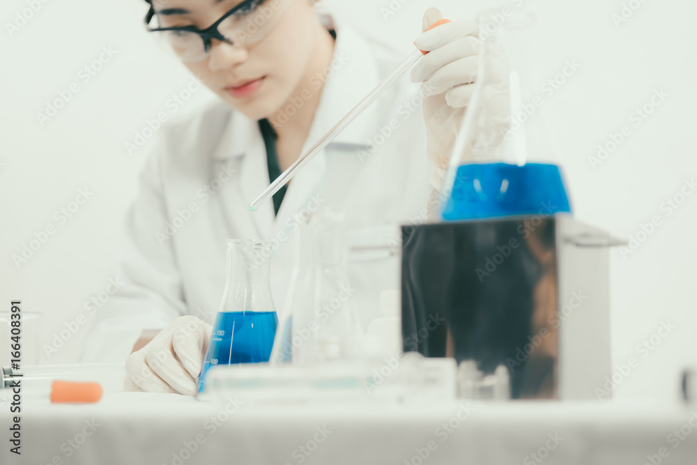 Young Asian scientist working in the lavatory with test tubes and other equipment to discover new drugs, products and methods of formulation