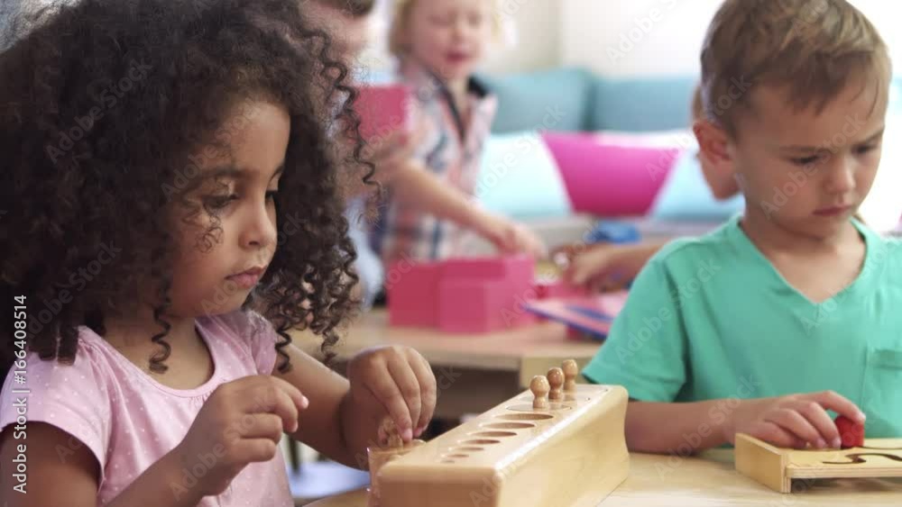 Montessori Pupils Working At Desk With Wooden Shape Puzzles