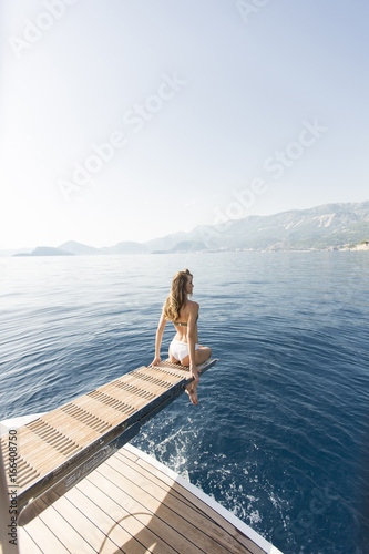 Young attractive woman sitting on luxury yacht floating at sea