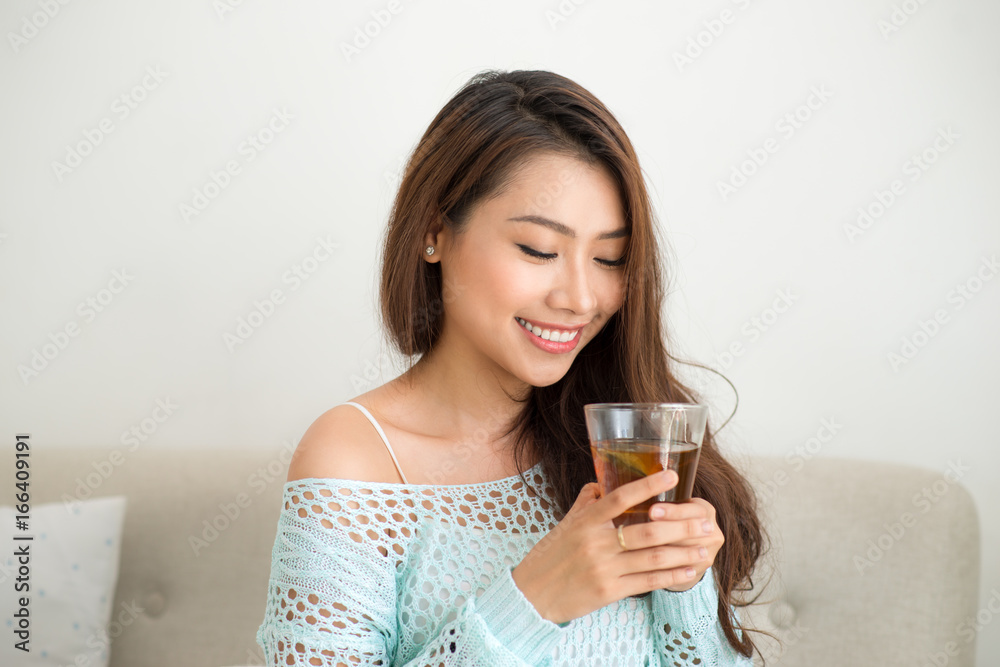 Beautiful young asian woman drinking her morning tea over a breakfast at home. Beautiful young asian woman drinking her morning tea over a breakfast at home.