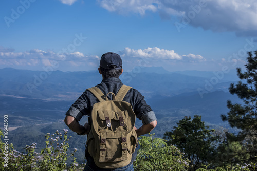 Young Man Traveler with backpack relaxing outdoor with rocky mountains on background Summer vacations and Lifestyle hiking concept.