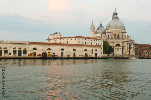 Basilica di Santa Maria della Salute at orange colors reflected on the water surface, Venice, Italy.