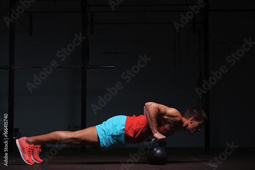 Muscular male adult exercising with kettle bells