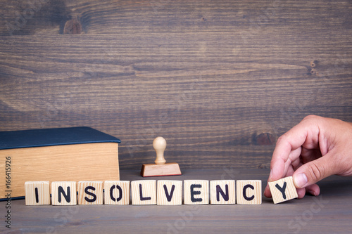 insolvency. Wooden letters on dark background. Office desk photo