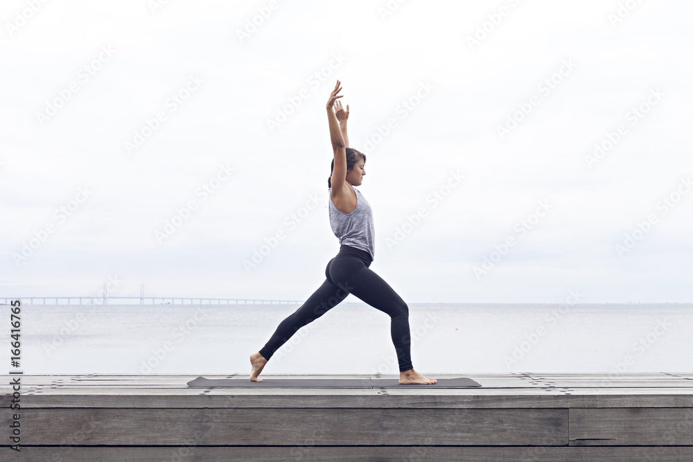 Woman doing yoga sun salutation by the sea Woman doing yoga sun salutation by the sea