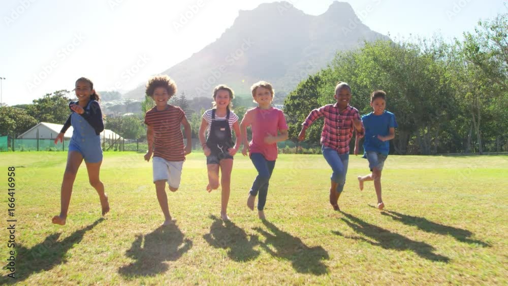 Six friends running towards camera in a park, front view