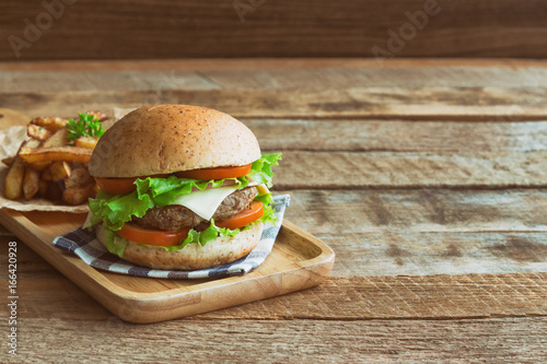 Homemade hamburger on plaid napkin with french fries. Delicious sandwich hamburger with meat or pork ham cheese and fresh vegetable. Hamburger or sandwich is the popular fast food for brunch or lunch.