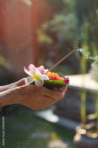 Woman holding canang sari - offering for Gods. Balinese tradition.