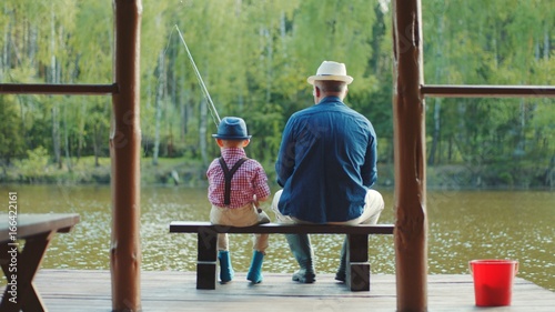 Little boy and hid grandpa are on fishing at the lake