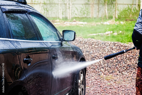 A man washes his car in the yard