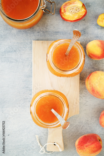 Apricot or peach jam in glass jars on wooden gray background 
