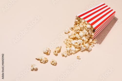 Popcorn in red and white cardboard with glass of soda