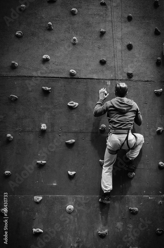 The guy climbs up the wall with insurance on the rope. Sports entertainment for climbers and climbers in the park.