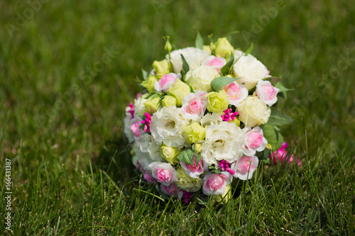 White green, pink and yellow and pink wedding bouquet with roses on the grass. Colorful image of beautiful nosegay