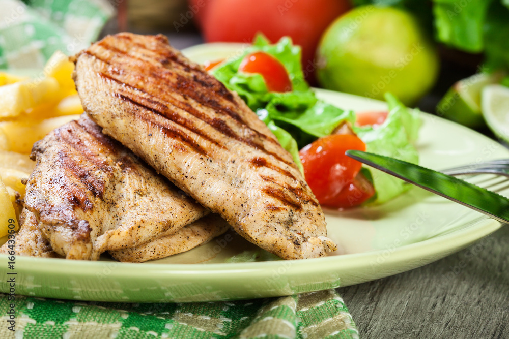 Grilled chicken breasts served with fries