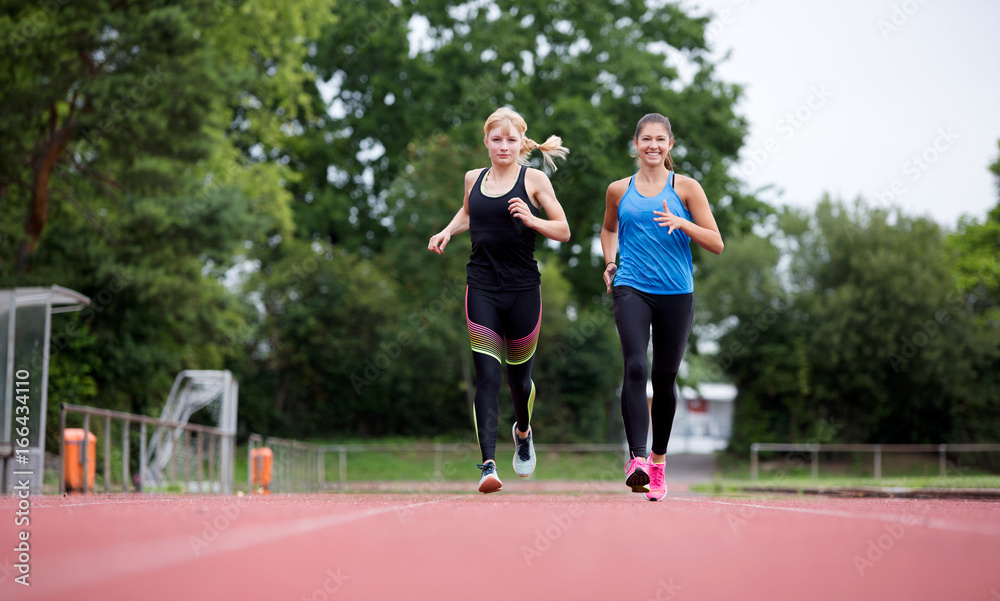 Zwei junge Frauen haben Spaß beim gemeinsamen Lauftraining