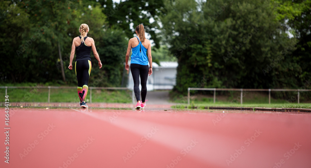 Rückenansicht: Junge Frauen machen beim Lauftraining eine Pause