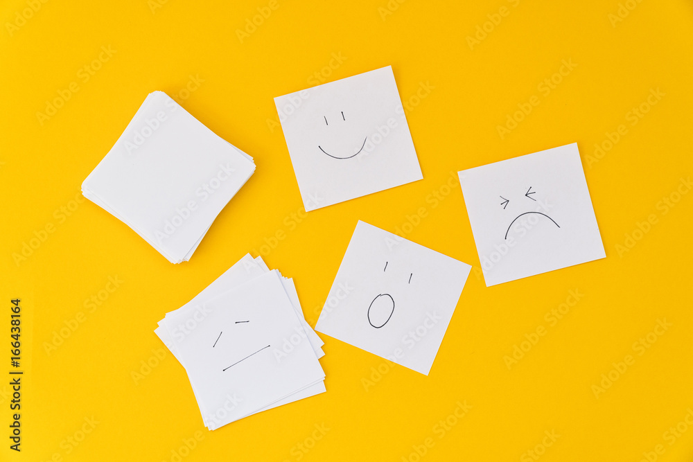 Emotions drawn on white sheets of paper are laid out on a yellow background Emotions drawn on white sheets of paper are laid out on a yellow background