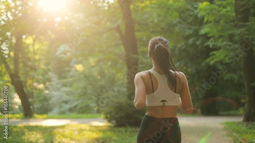 Back view of the young attractive woman running in the park at the early morning.