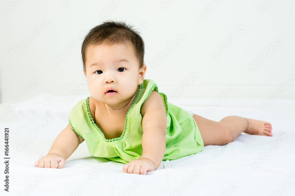 Portrait of adorable infant baby girl with saliva lying on the tummy on bed Portrait of adorable infant baby girl with saliva lying on the tummy on bed