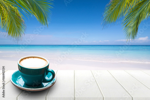 Coffee in cup on wooden table with sea view background in summer. © satit
